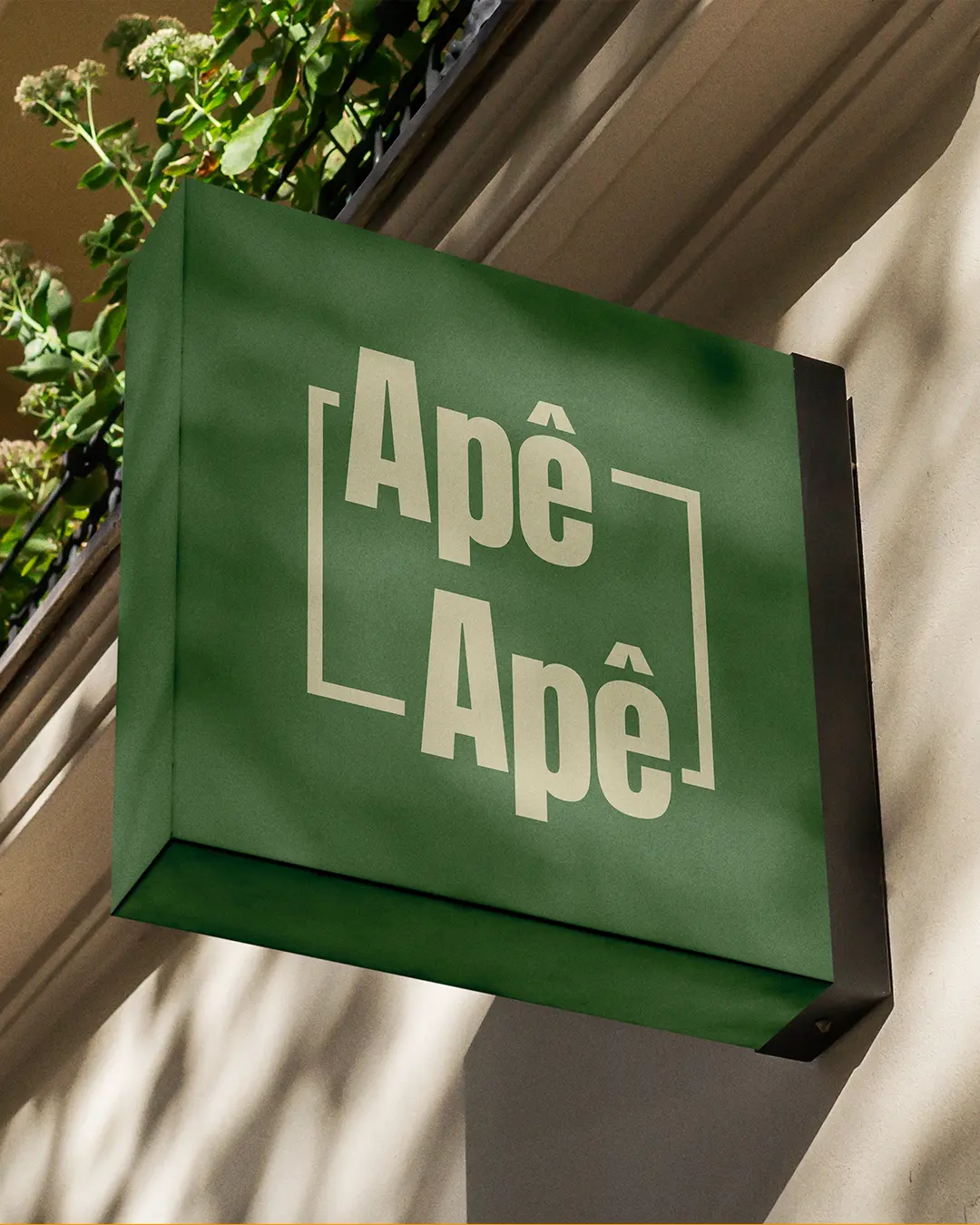 Identidade visual Apê Apê aplicada em uma placa verde